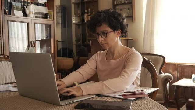 Home office working environment. Using laptop and working efficiently. Using technology and working at home productively. Young female adult study focused.