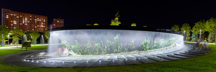 Waterfall flows in streams into granite bed of artificial river. Fountain in form of huge bowl.