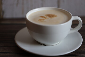 coffee in white cup with saucer on wooden table with wooden bottom
