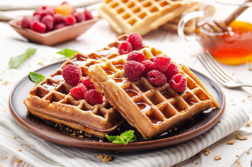 Homemade crispy Belgian waffles served with raspberries and honey