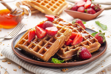 Homemade crispy Belgian waffles served with strawberries and honey