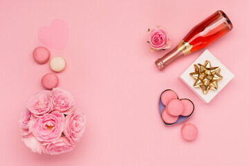 Flowers, bottle of wine, sweets on pink background. Valentines day concept. Flat lay, top view, copy space.
