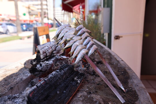 Elaboration of Malaga's espetos al carb&oacute;n with the beach in the background. Sardines