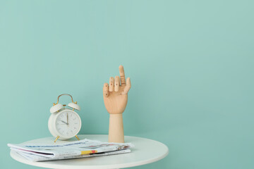 Wooden hand with clock and newspaper on table