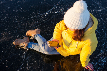 Fototapeta na wymiar girl sitting on ice with phone