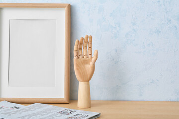 Wooden hand with photo frame and newspaper on table