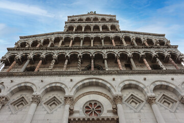 Statue of St. Michael the Archangel perched atop the Church of San Michele in the Tuscan village of Lucca Italy . Sculpture has blue eyes and wings. The ornate facade dates to the 13th century.
