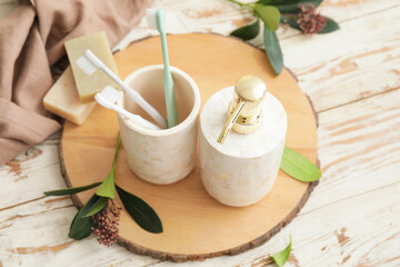 Board with dispenser and toothbrushes on wooden table