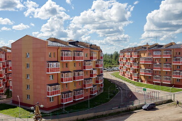 Residential brick houses with a sidewalk between them on a summer sunny day in the village of Taezhny, Krasnoyarsk Territory. Russia.