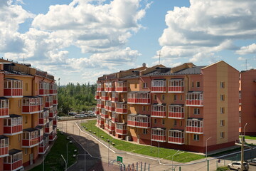 New residential brick houses with a sidewalk between them on a summer sunny day in the village of Taezhny, Krasnoyarsk Territory. Russia.