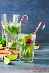Glasses of fresh strawberry mojito on color background