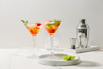 Glasses of strawberry mojito on white table