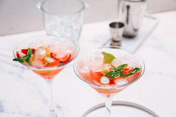 Glasses of strawberry mojito on white table