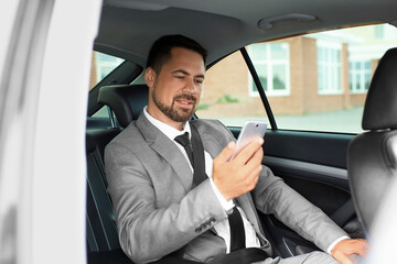 Successful businessman with mobile phone in modern car