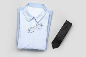 New male shirts, glasses and tie on light background