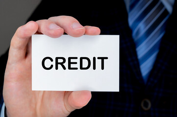 Close-up of man's hand holding and showing visiting card with CREDIT word on it.