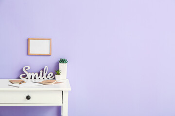 Stylish workplace with blank photo frame near color wall