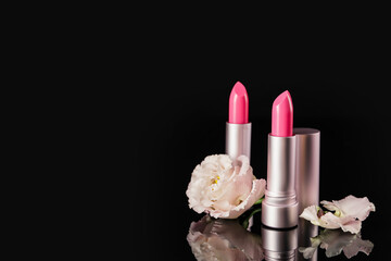 Beautiful lipsticks and flower on black background