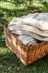 Obraz premium Handmade knitted beige plaid in basket.