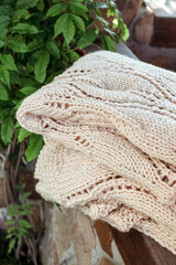 Handmade knitted beige plaid in basket.