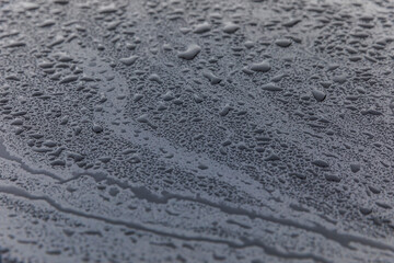 Raindrops on a black car hood