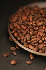 Pine nuts in shell close-up in a  matte plate on a black slate background.heap of pine nuts. food and cosmetics raw materials.healthy snack.Clean eco-friendly product.Vegetarian and vegan food 