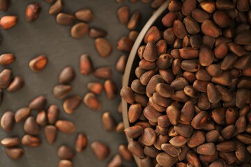 Pine nuts in shell close-up in a dark matte plate on a black  background.heap of pine nuts. food and cosmetics raw materials.healthy snack.Clean eco-friendly product.Vegetarian and vegan food 