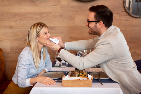 Young couple in the restaurant and have a romantic dinner. the guy wipes his mouth with a napkin to the girl.