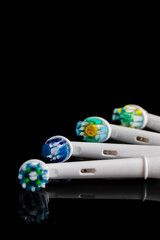 Four Spare Attachments for Electric Toothbrush On Black Surface.