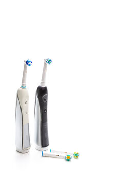 Pair of Professional Electric Toothbrushes of Black and White Colors With Spare Attachments Together on White Background.