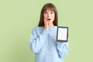 Naklejka premium Surprised young woman with e-reader on color background