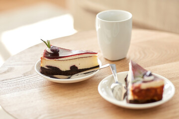 food, junk-food, culinary, baking and holidays concept - piece of delicious cherry chocolate layer cake on saucer with spoon on wooden table