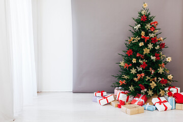 decorated Christmas tree with New Year's gifts in a room with a window