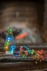 Christmas tree with lights on the background of a stone fireplace with wood. cozy house, waiting for Christmas.