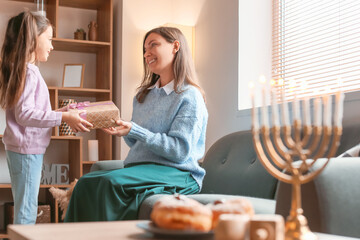 Happy little girl with mother celebrating Hannukah at home