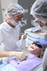 The dentist and assistant perform professional dental cleaning for the patient. Protective screen...