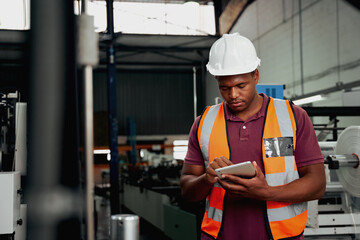 Young african american industrial worker working on digital tablet in the factory - you black male checking modern machinery