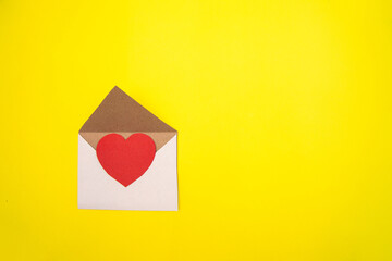 Paper heart in an envelope on a yellow background.Valentine's day gift.Heart made of red cardboard.