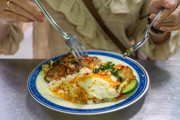 Vietnamese girl eating Com tam - a Vietnamese broken rice with pickles steak grilled pork ribs cucumber onion oil sweet chilies garlic fish sauce fried egg omelet Asian cuisine