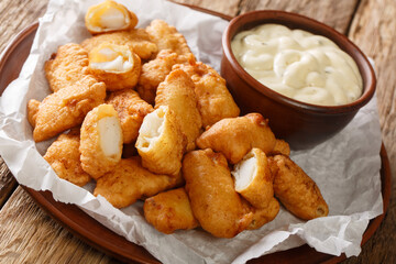 Kibbeling is a Dutch snack consisting of battered chunks of fish, commonly served with a mayonnaise based garlic sauce closeup in the plate on the table. horizontal