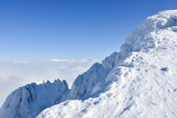 Obraz premium Winter mountain. Snowy peak high above the clouds. Show and clouds on Dry Mountain, Serbia