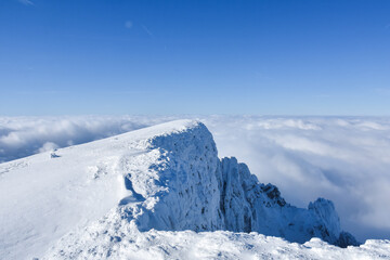 Obraz premium Winter mountain. Snowy peak high above the clouds. Show and clouds on Dry Mountain, Serbia