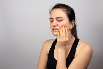 A woman holds a sore tooth with her hand. Dental pain in dentistry, pulpitis and tooth decay, nerve removal. Stomatitis and gingivitis, infectious inflammation. A banner for the dentist and medicine