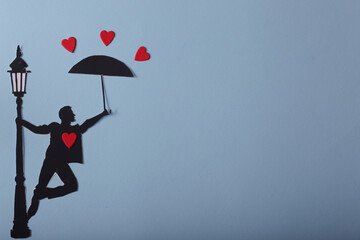 silhouette of a man with an umbrella and hearts on blue background