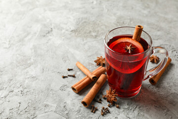Glass of mulled wine and cinnamon on gray background