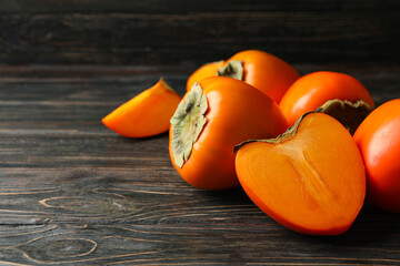 Fresh ripe persimmon on wooden background, space for text