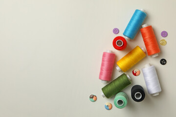 Sewing threads and buttons on white background, space for text