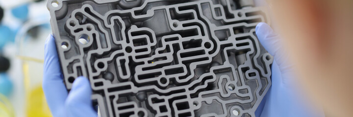 Hands in rubber gloves hold automatic transmission in crooked view. Car repair and service concept.