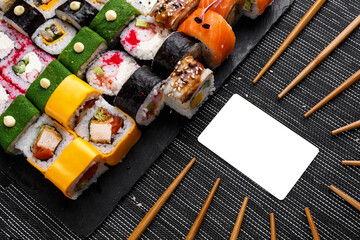 Huge set of colored rolls with different stuffing. Blank white card for inscription, circle of wooden chopsticks.