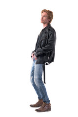 Naklejka premium Side view of stylish handsome redhead man in biker leather jacket posing looking up bend backward. Full body length isolated on white background. 